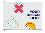 A white customizable flag or banner with a metal grommet on the left side. The banner features placeholder graphics and the text 'YOUR DESIGN HERE' in navy blue, with sample geometric shapes in pink, yellow, and teal.
